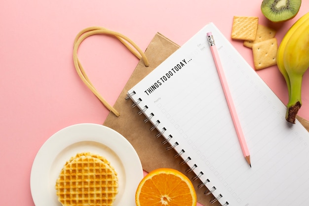 Notebook with a pen, fruits, and a cup of tea on a table