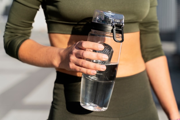 Gym-goer drinking water from a reusable bottle