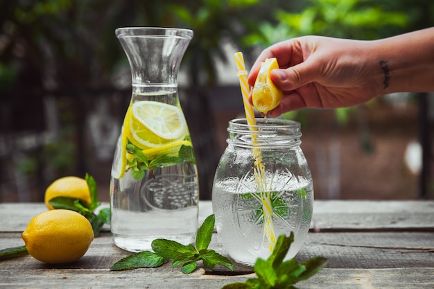 Glass jar with cucumber, lemon, and mint slices in water