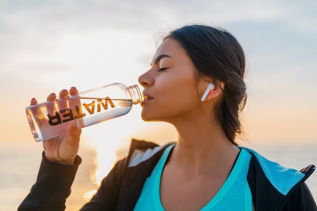 Person drinking water and using a foam roller after stretching