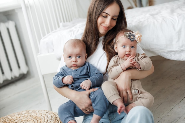 A smiling mother playing with twins in a sunlit living room