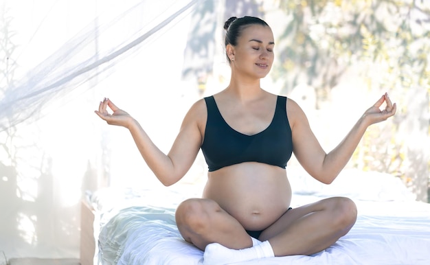 Pregnant woman doing yoga in a hotel room