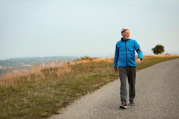 Senior man walking with good posture on a paved path