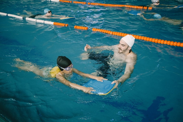 Teen practicing swimming drills with kickboard